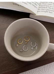 Vue détaillée de boucles d'oreilles trèfle en argent et or sur une coupelle en céramique