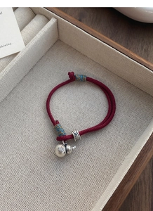 Detailed shot of red woven bracelet with silver gourd charm and Fu character engraving