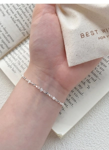 Detailed view of silver rose bracelet with leaf links worn by a model on a vintage background