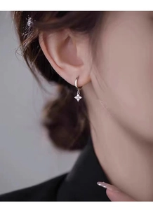 Gros plan sur créole en argent S925 avec pendentif fleur à quatre feuilles scintillant