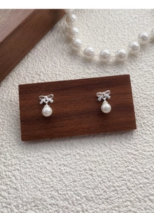 Close-up of S999 sterling silver bow earrings with elegant white pearl pendant dangles