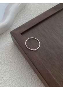 Macro shot of minimalist S925 sterling silver ring with shimmering textured finish on wood