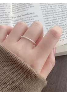 Detail of a sparkling sterling silver slim ring worn by a model in a warm setting