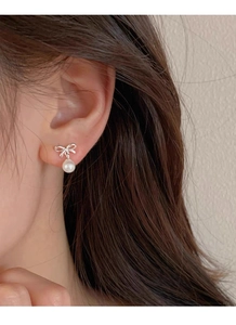 Close-up of elegant S999 silver bow earrings with round white pearls worn by a model