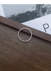 Macro detail of S925 sterling silver ring with shimmering diamond-cut texture on dark wood