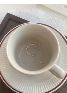 Close-up of S925 sterling silver chain ring with pearl charm on a minimalist white background