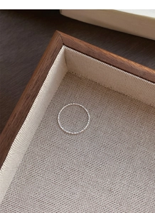 Detail of s925 silver wavy textured ring displayed on a rustic walnut wood tray