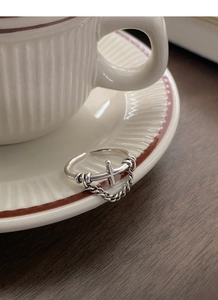 Detail view of S925 sterling silver vintage cross ring with hanging chain on ceramic