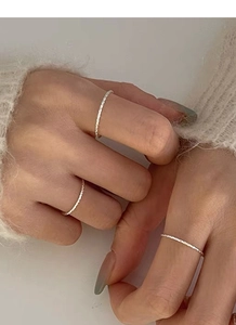Detail of stacked slim S925 silver rings with textured finish on a model hand