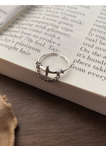Macro shot of S925 vintage silver chain cross ring placed on an open antique book