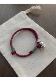 Detail of S999 silver gourd charm with Fu character on hand-woven red rope bracelet