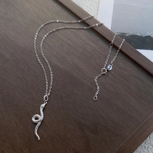 Elegante S999 Silberne Schlangenkette mit grünen Edelsteinaugen und Schuppen auf Holztablett