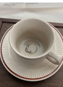Close-up of S925 sterling silver chain ring on a coffee cup with minimalist aesthetic