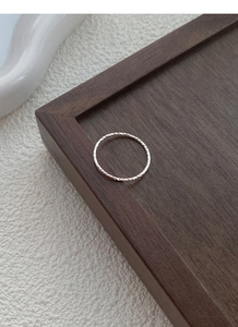 Close-up of sparkling S925 sterling silver thin ring with twisted textured finish