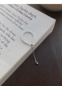Detail of S925 sterling silver chain ring featuring a dangling bead on an open book