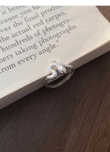 Détail de la bague serpent en argent S925 avec texture d'écailles sur une page de livre