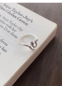 Gros plan d'une bague serpent en argent S925 montrant les écailles et le poinçon