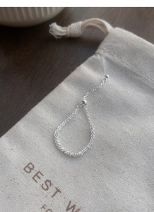 Close-up of adjustable S925 sterling silver chain ring on a textured fabric pouch