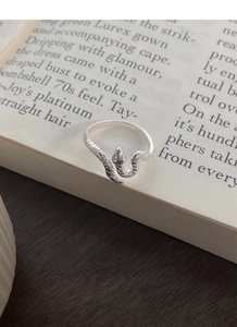 Gros plan d'une bague serpent en argent S925 avec écailles texturées sur livre ancien