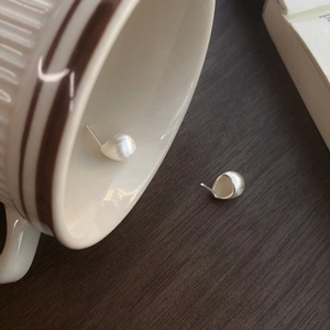 Minimalistische S925 Silber Bohnen-Ohrstecker mit gebürstetem Matt-Finish auf Keramiktasse
