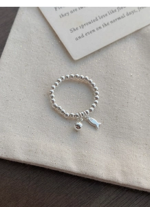 Vue macro d'une bague en perles d'argent S925 avec un pendentif poisson minimaliste