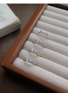 Detail of four S925 silver rings with marquise-cut crystals on a wooden jewelry tray