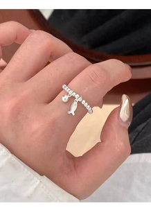 Détail d'une bague élastique en argent S925 avec breloque poisson sur doigt de femme