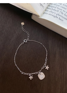 Detailed close-up of S925 sterling silver daisy bracelet with star pendants on wood