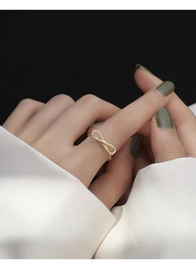 Detail view of a minimalist golden hollow bow ring worn by a model in soft lighting