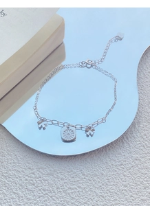 Close-up of S925 silver bracelet featuring daisy pendant and delicate bow charms