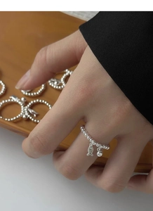 Détail de la bague élastique en argent avec charms poisson et boule portée au doigt