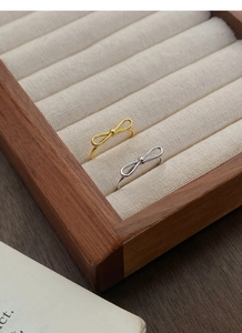 Macro detail of silver and gold bow rings displayed in a luxury wooden jewelry box