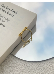 Detailed shot of a gold hollow bow ring on a reflective mirror with soft blue sky reflection