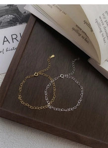 Detail of S925 sterling silver heart link bracelets in gold and silver on wood tray