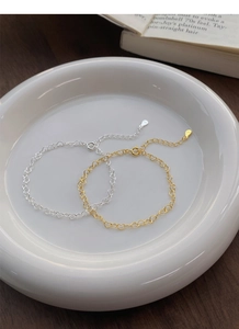 Detail showing gold and silver S925 sterling silver heart link bracelets in a ceramic bowl