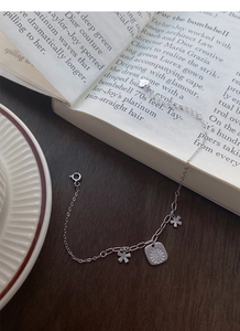 Detail view of S925 sterling silver daisy bracelet with heart charm on a wooden table