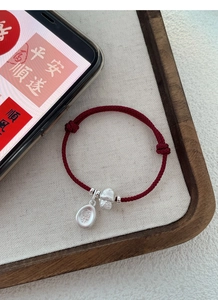 Macro detail of red woven rope bracelet with silver happiness pendant and festive charm