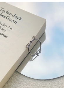 Detailed view of silver bow ring on a mirror reflecting blue sky with vintage book