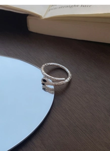 Detail of silver snake ring featuring black gemstone eyes and textured scale engraving