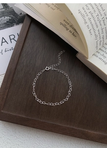 Close-up of S925 sterling silver heart chain bracelet on vintage wooden tray with Paris cards