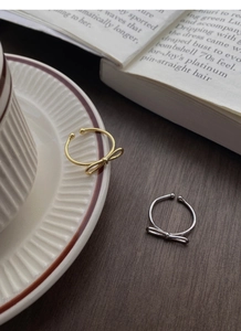 Detail of elegant gold and silver bow rings with an adjustable open band design