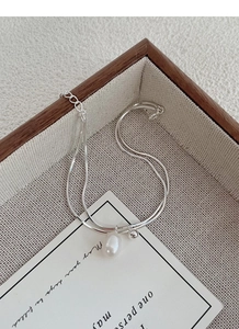 Detail of silver double-layer snake chain with drop pearl pendant on an elegant tray