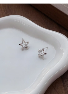 Macro shot of S999 sterling silver star earrings with brilliant zircon inlays on ceramic tray