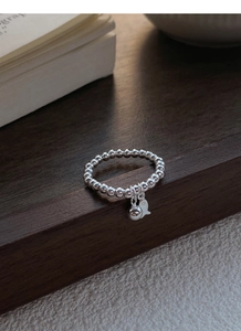 Vue macro d'une bague en perles d'argent S925 avec pendentifs boule et poisson polis
