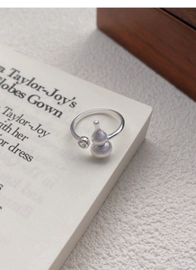 Macro shot of silver hulu ring with matte finish and small cubic zirconia on book page