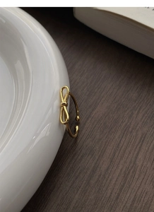 Macro shot of gold bow knot ring on white porcelain edge with wood background