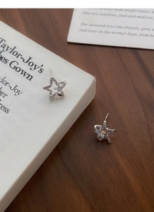 Close-up of S999 sterling silver star earrings with pavé zircon stones on book pages