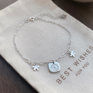 Elegant S925 sterling silver daisy bracelet with floral charms on a linen bag