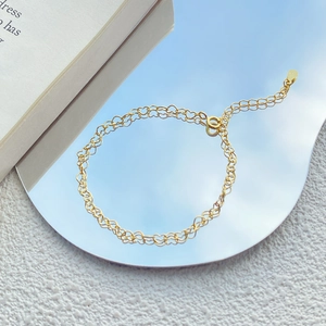 Elegant gold S925 sterling silver heart chain bracelet reflecting blue sky on a mirror