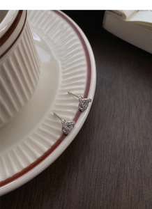 Detail of S999 silver twisted triangle stud earrings with shimmering zircon inlays